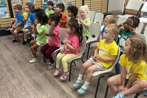 K3 - K4 four sitting in rows listening to a teacher.