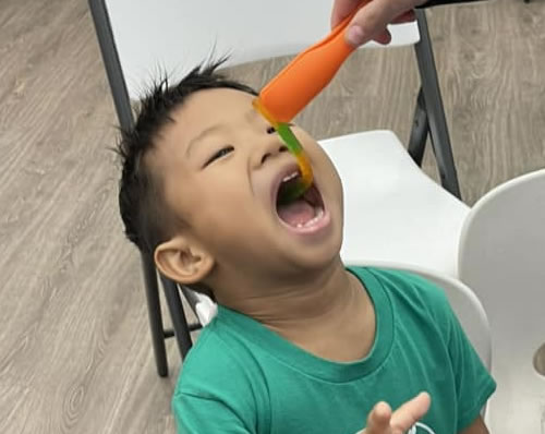 Student having fun eating a gummy worm.