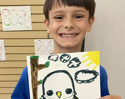 A student displaying his eagle drawing for the fourth of July.