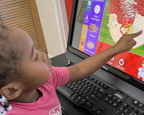 A student using a computer to build a pizza.